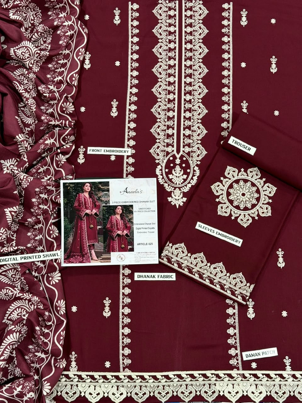Close-up of delicate white geometric and floral embroidery on premium deep maroon Airjet Dhanak fabric.