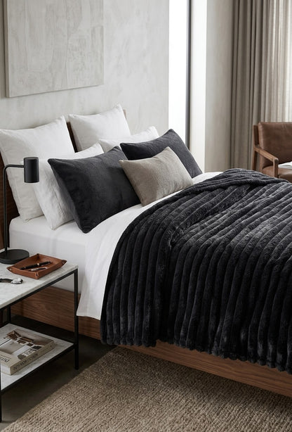 Dark charcoal king size fleece AC blanket with ribbed texture on a double bed.
